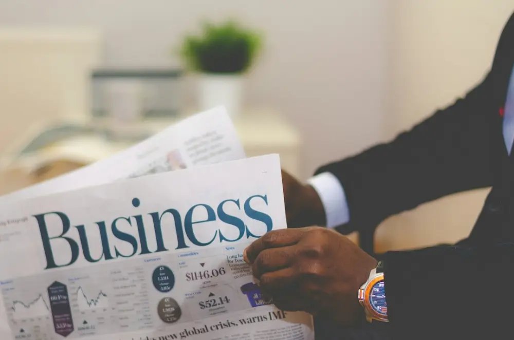 Person wearing suit reading business newspaper, illustrating business applications